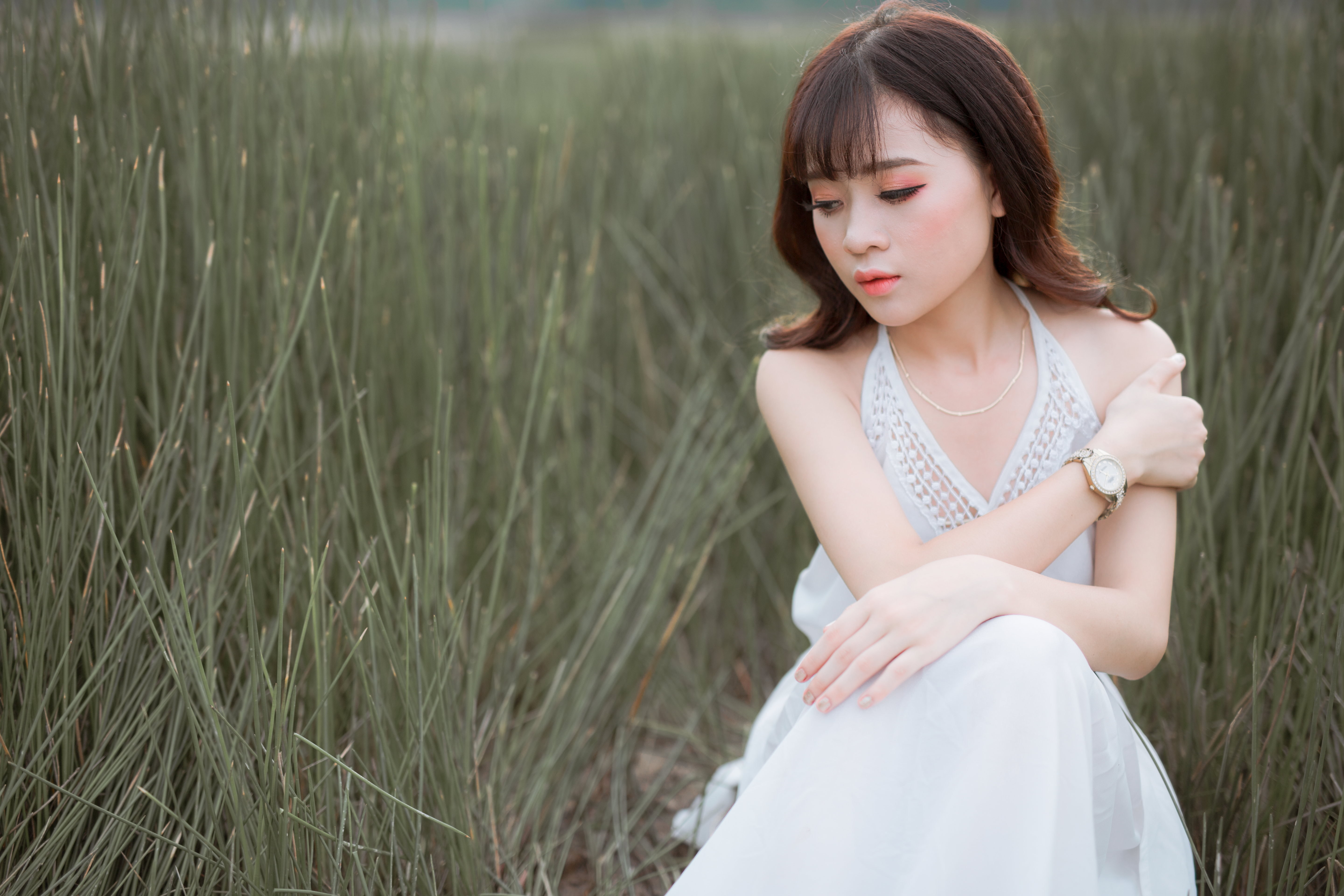 Woman wearing white halter dress surrounded by grass photo
