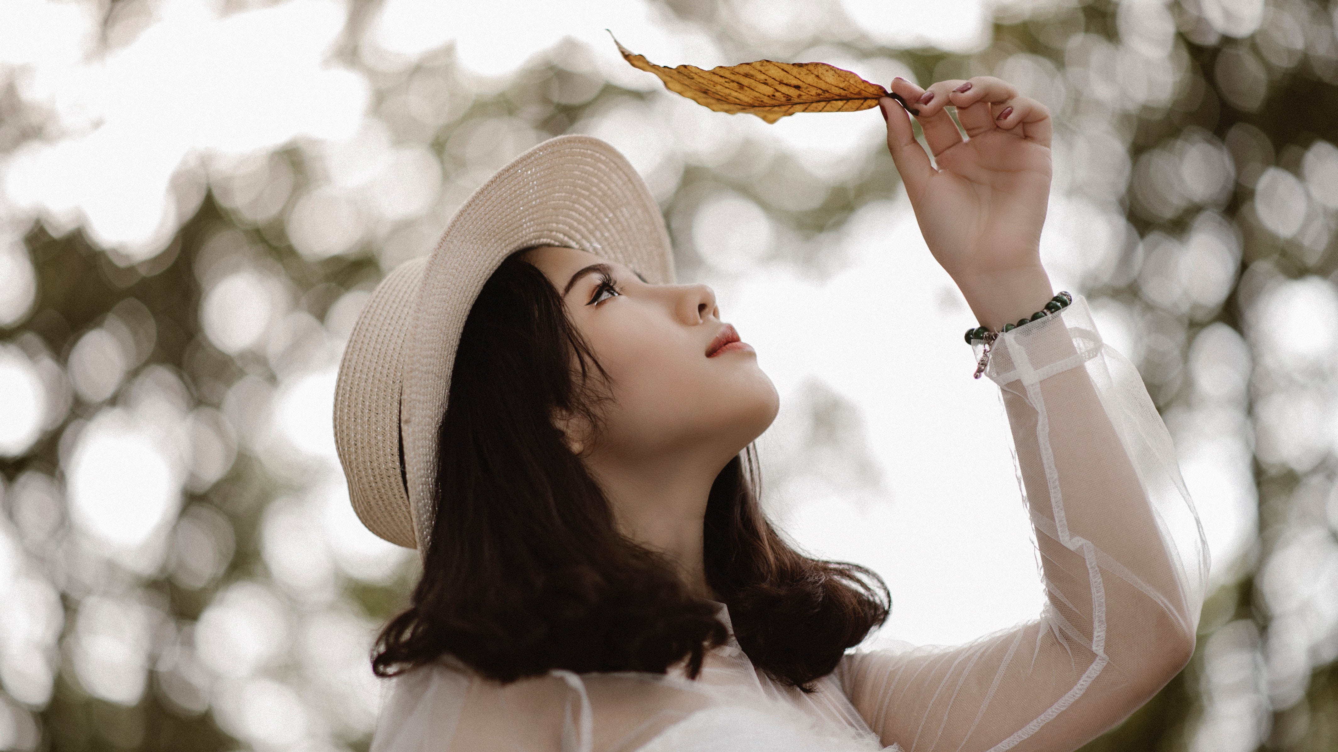 Woman wearing white long sleeve scoop-neck top while holding brown leaf photo