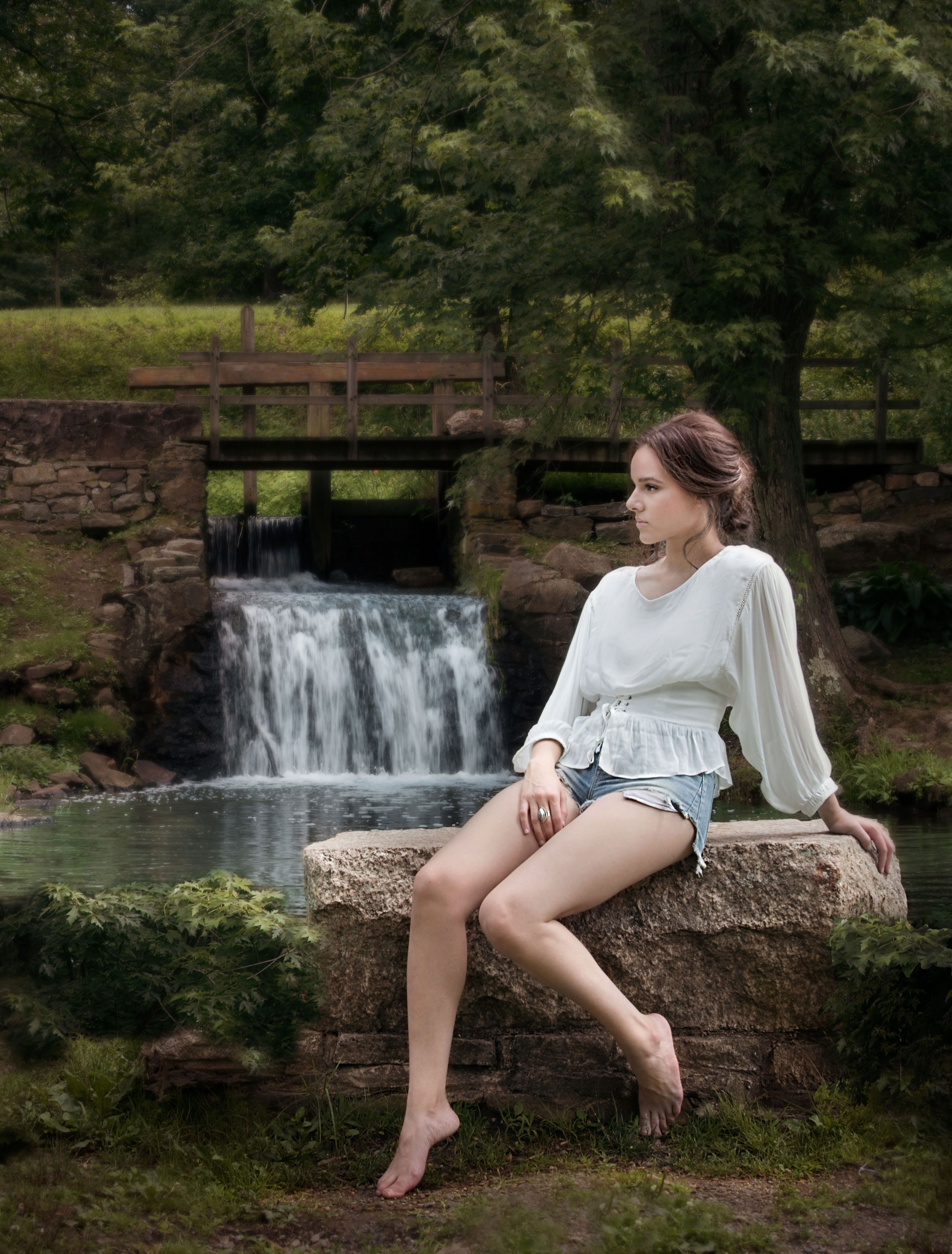 Woman wearing white long sleeve shirt sitting near waterfalls photo