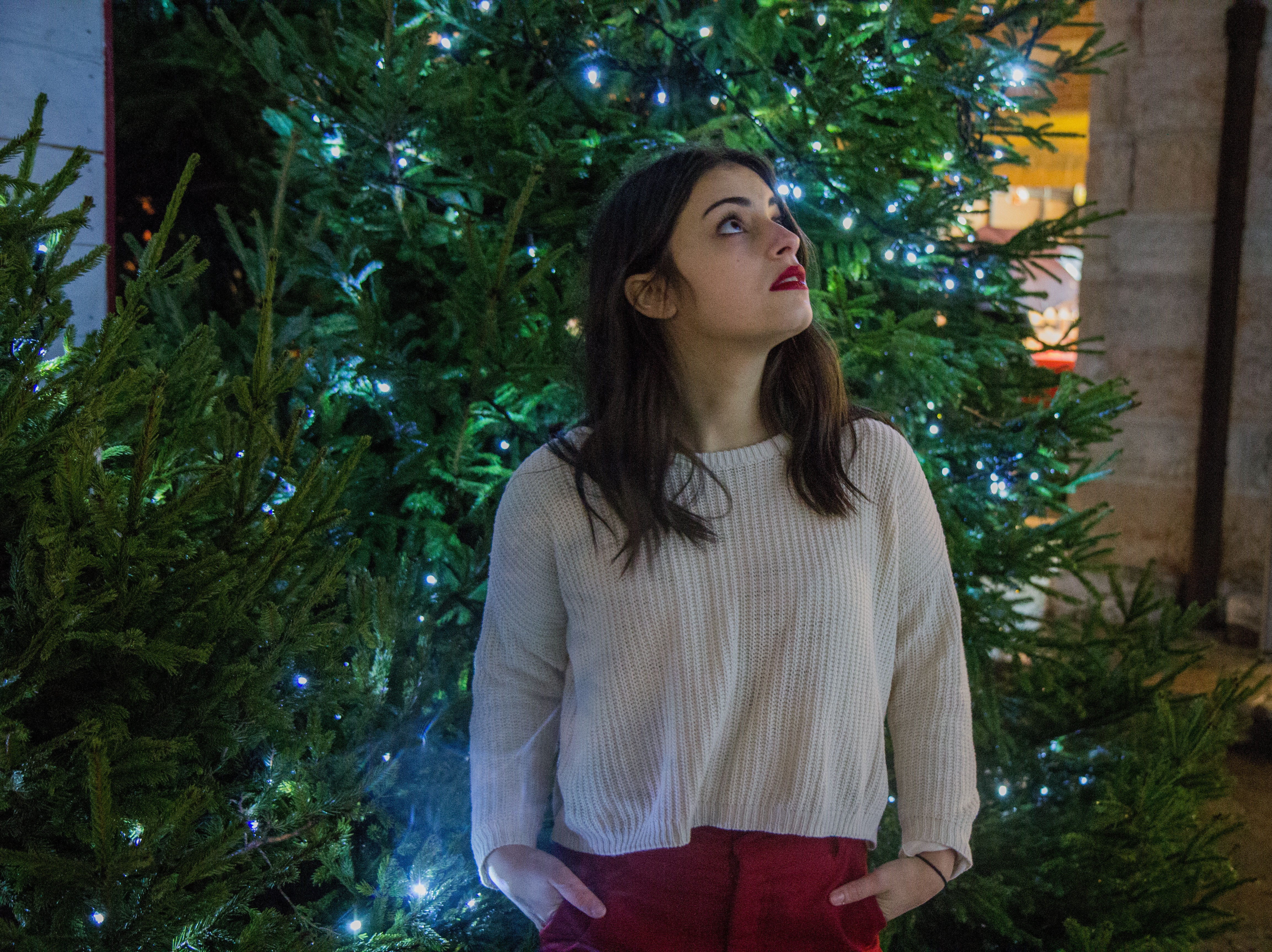 Woman wearing white sweater with red skirt near green christmas tree photo