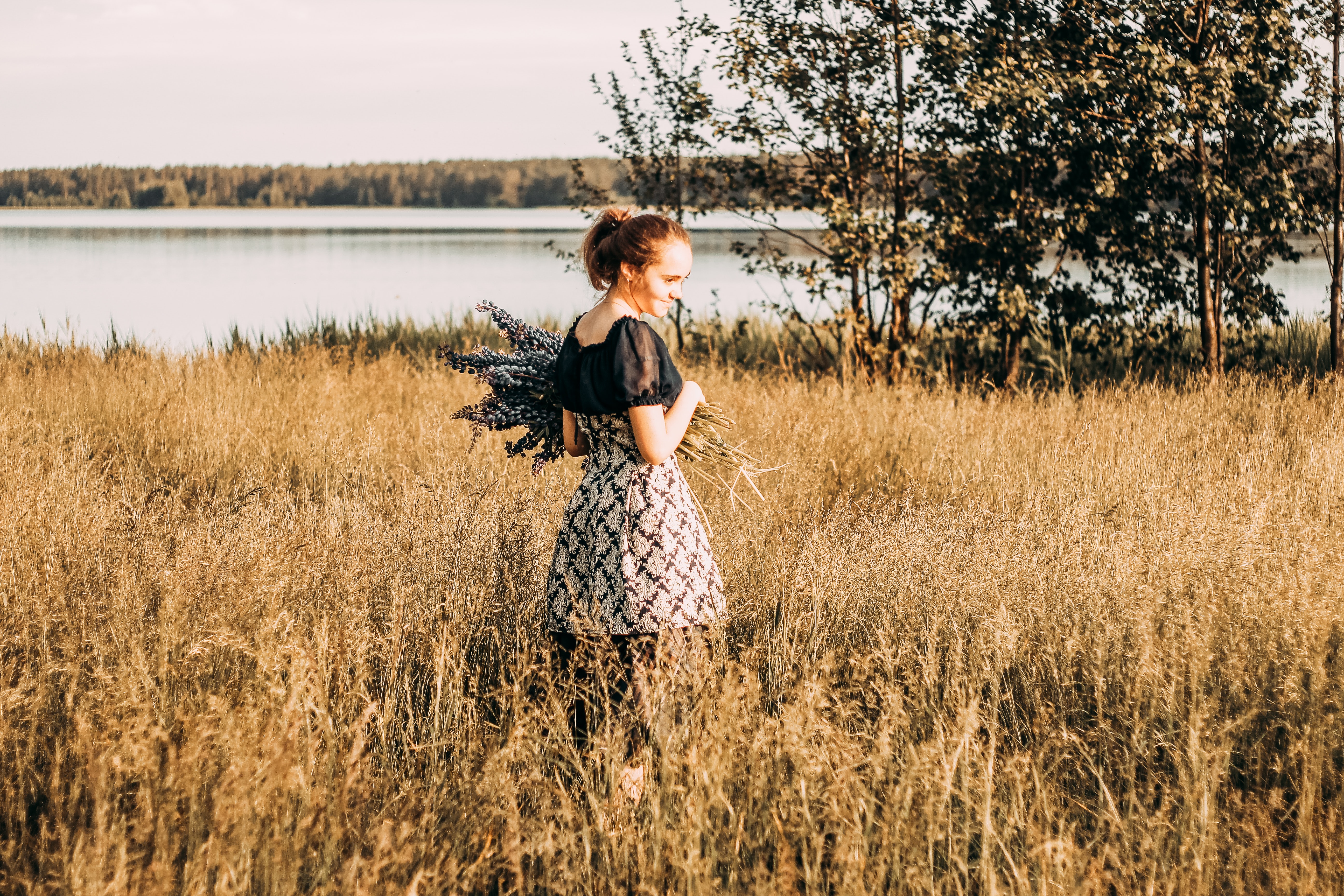 Woman wears black and grey dress stands in field photo