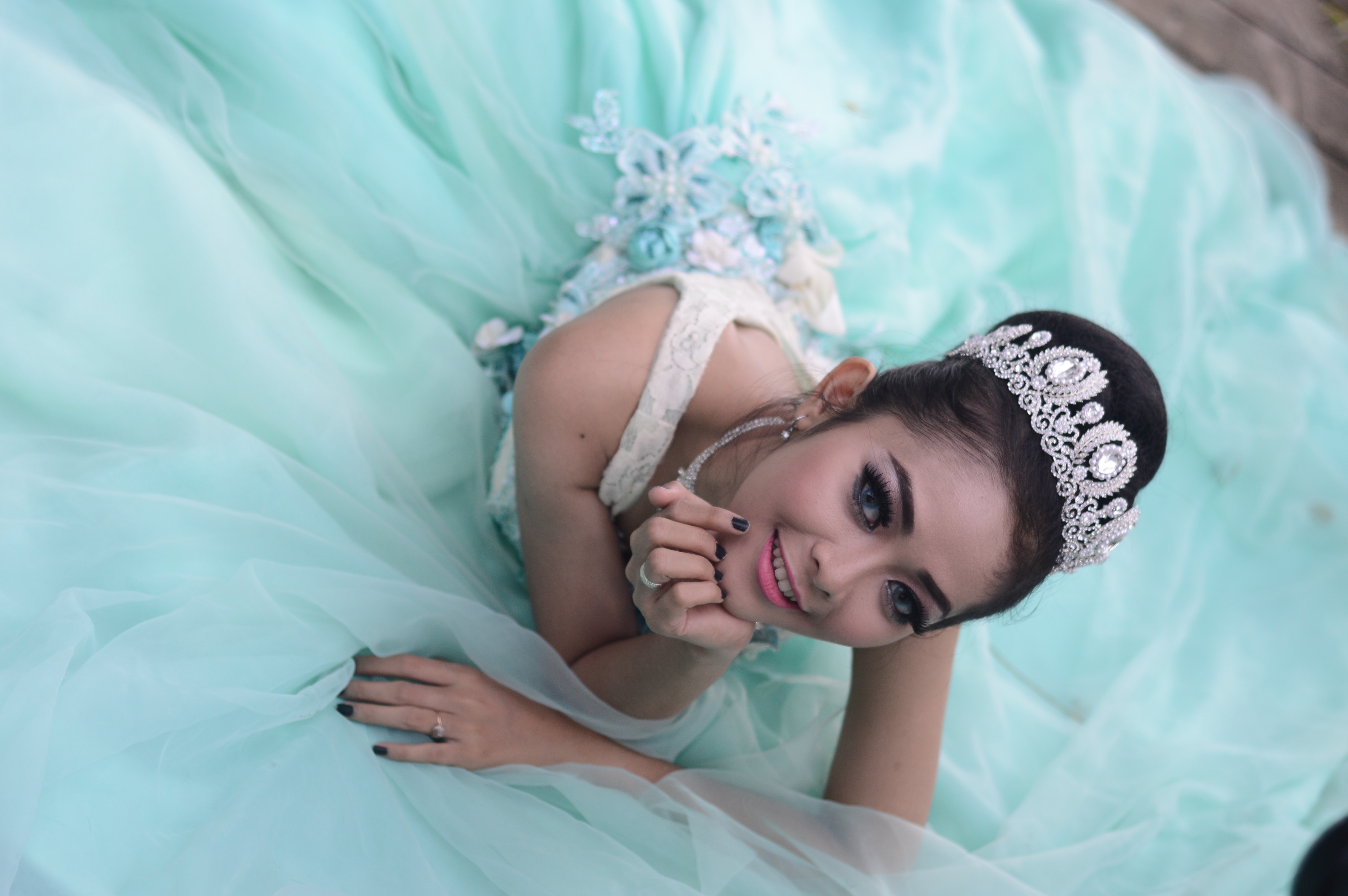 Woman wears teal chiffon gown and crown photo