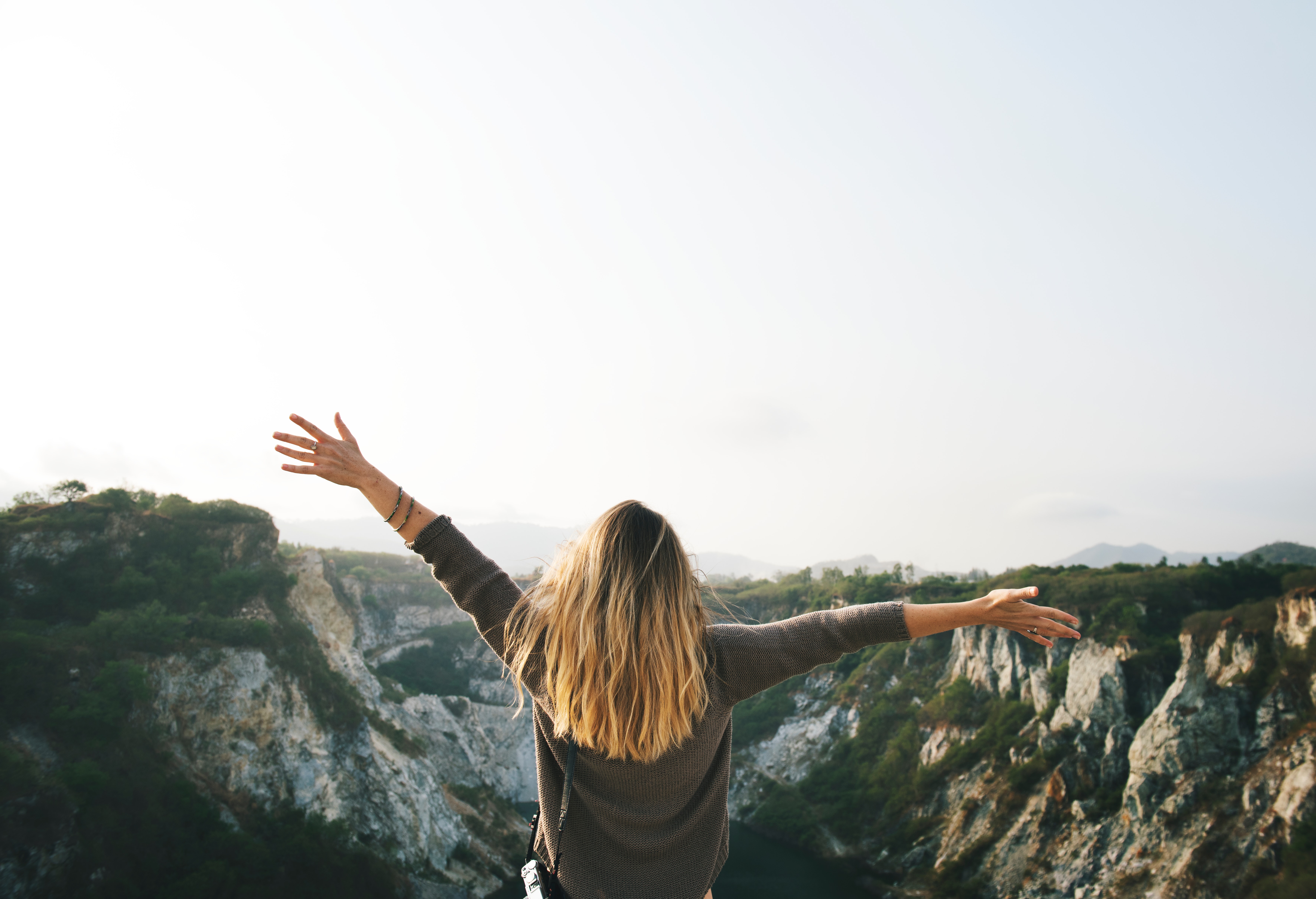 Woman with blonde hair at the top of the mountain raising her hands photo