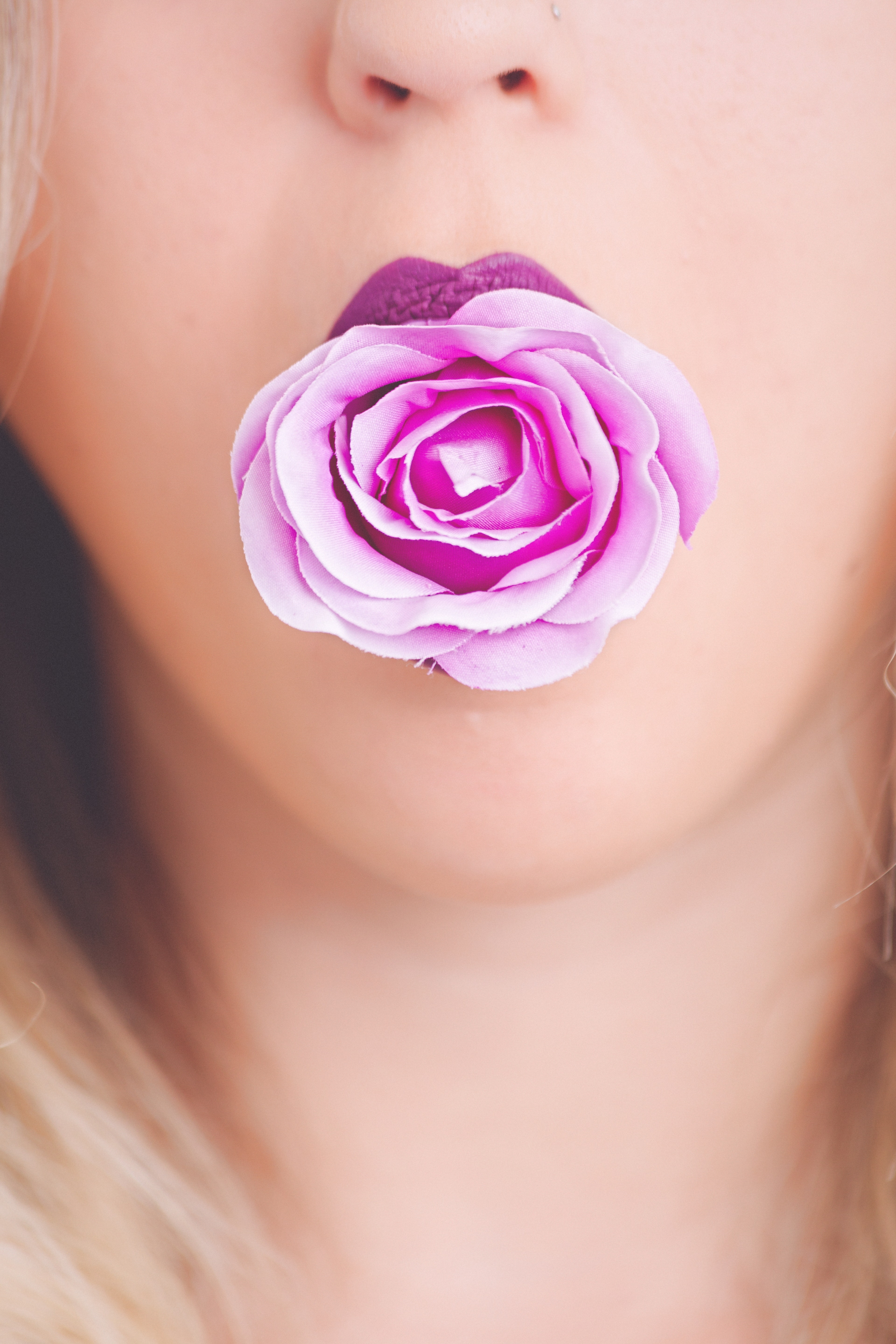 Woman with pink flower in the mouth photo