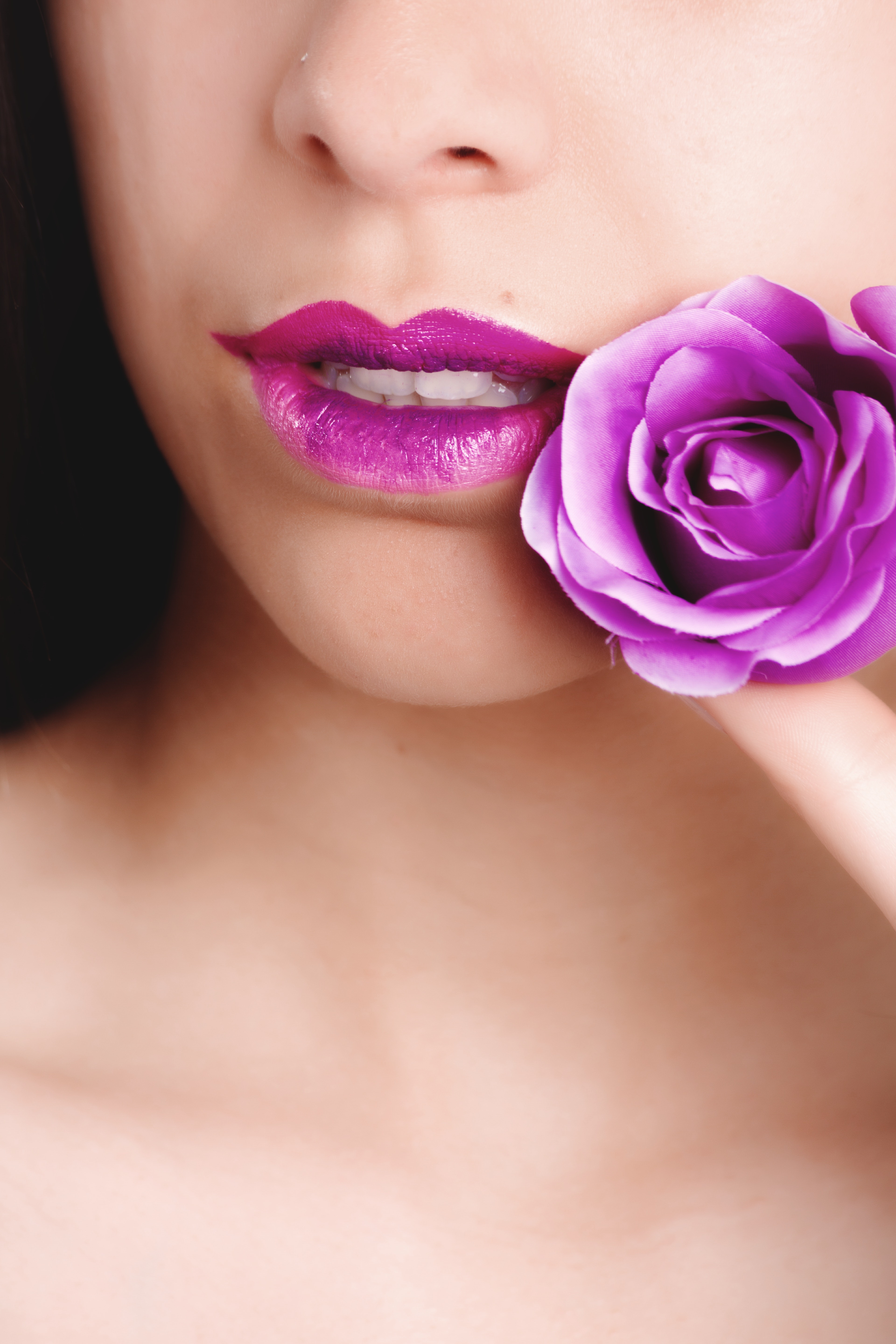 Woman with pink lipstick holding pink rose photo