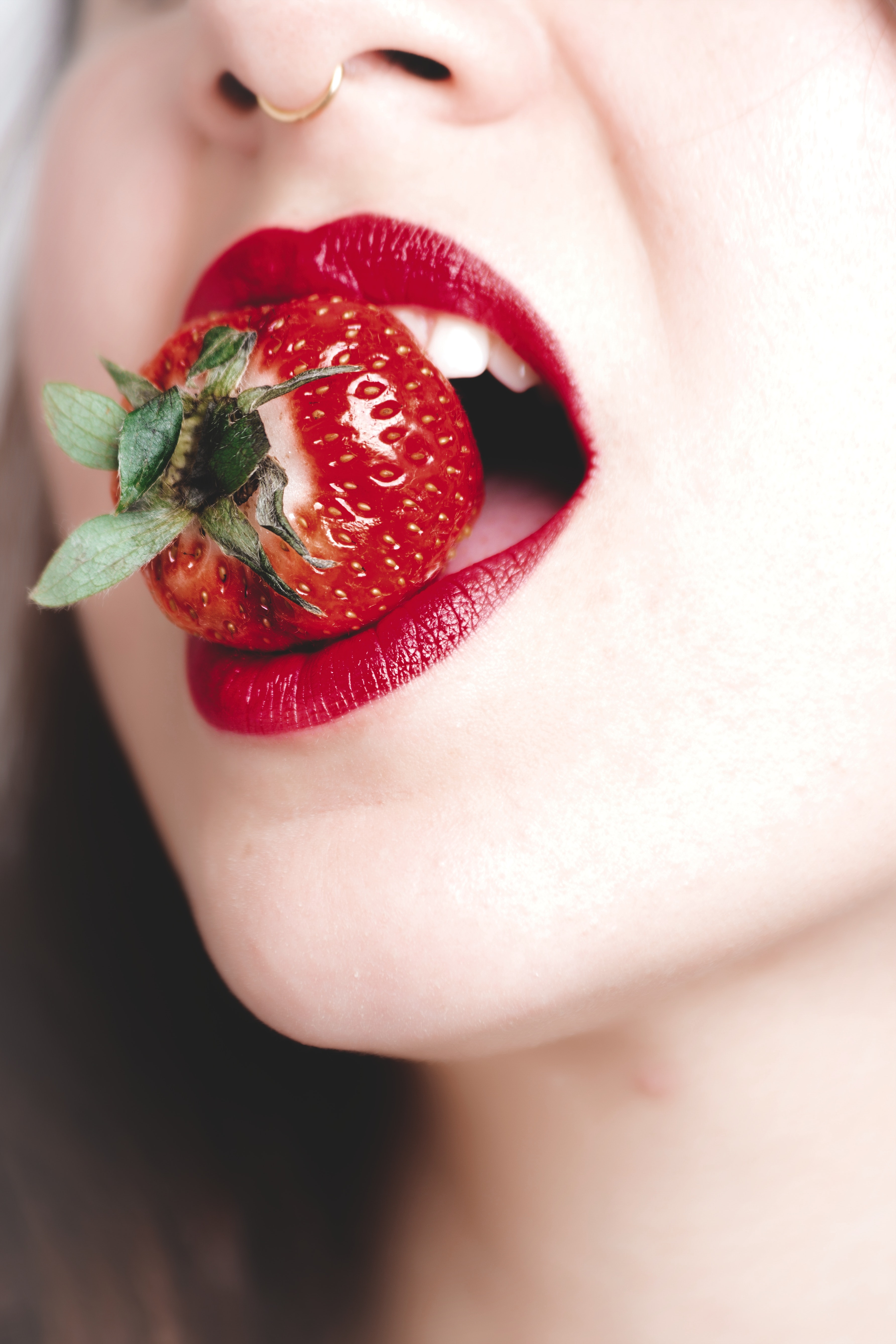 Woman with red lipstick biting strawberry photo