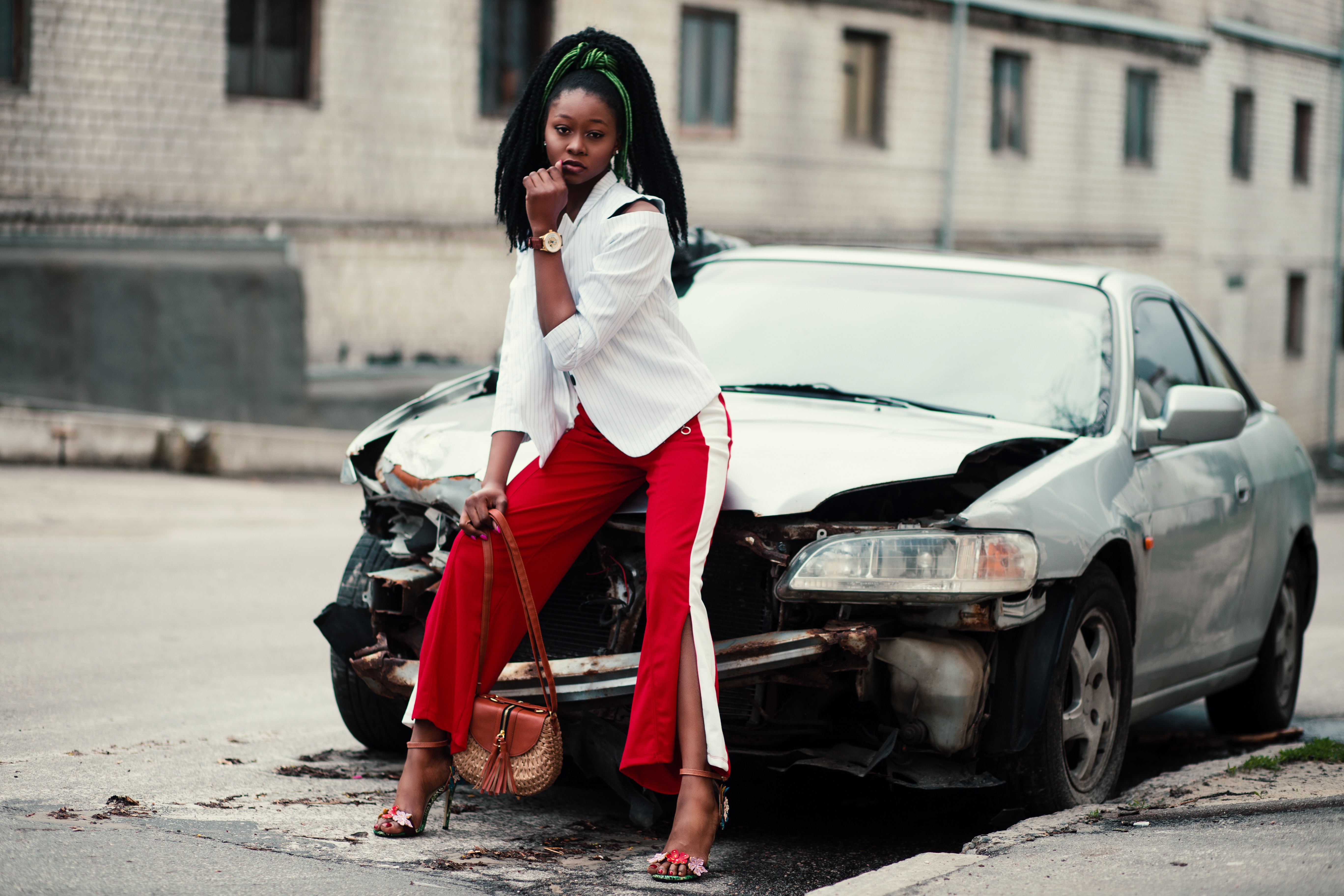 Woman with white long-sleeved shirt, red ,and white slit pants and pair of black open-toe d'orsay heel sandals sitting on wrecked silver car photo