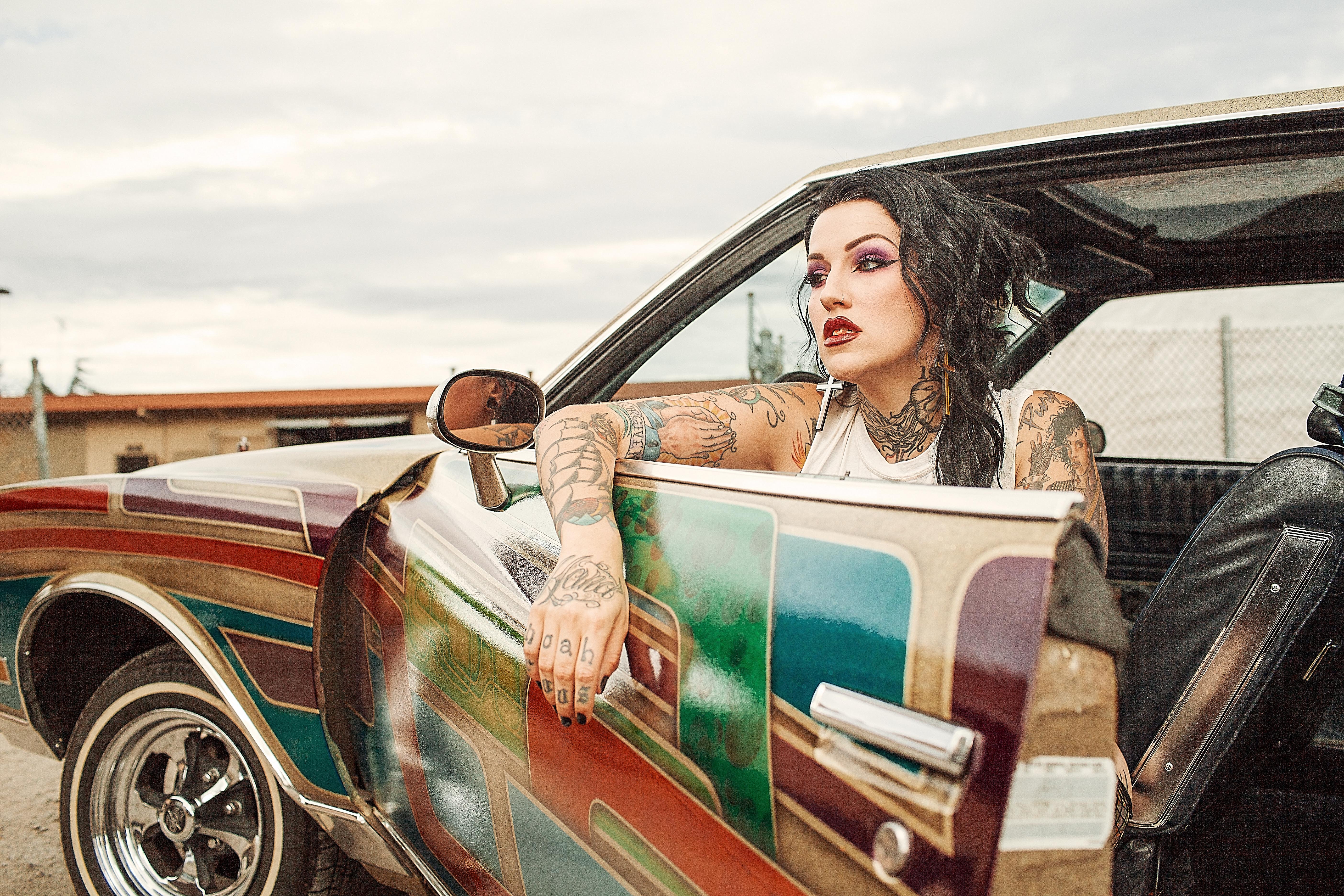 Woman with white tank top inside classic multicolored car photo
