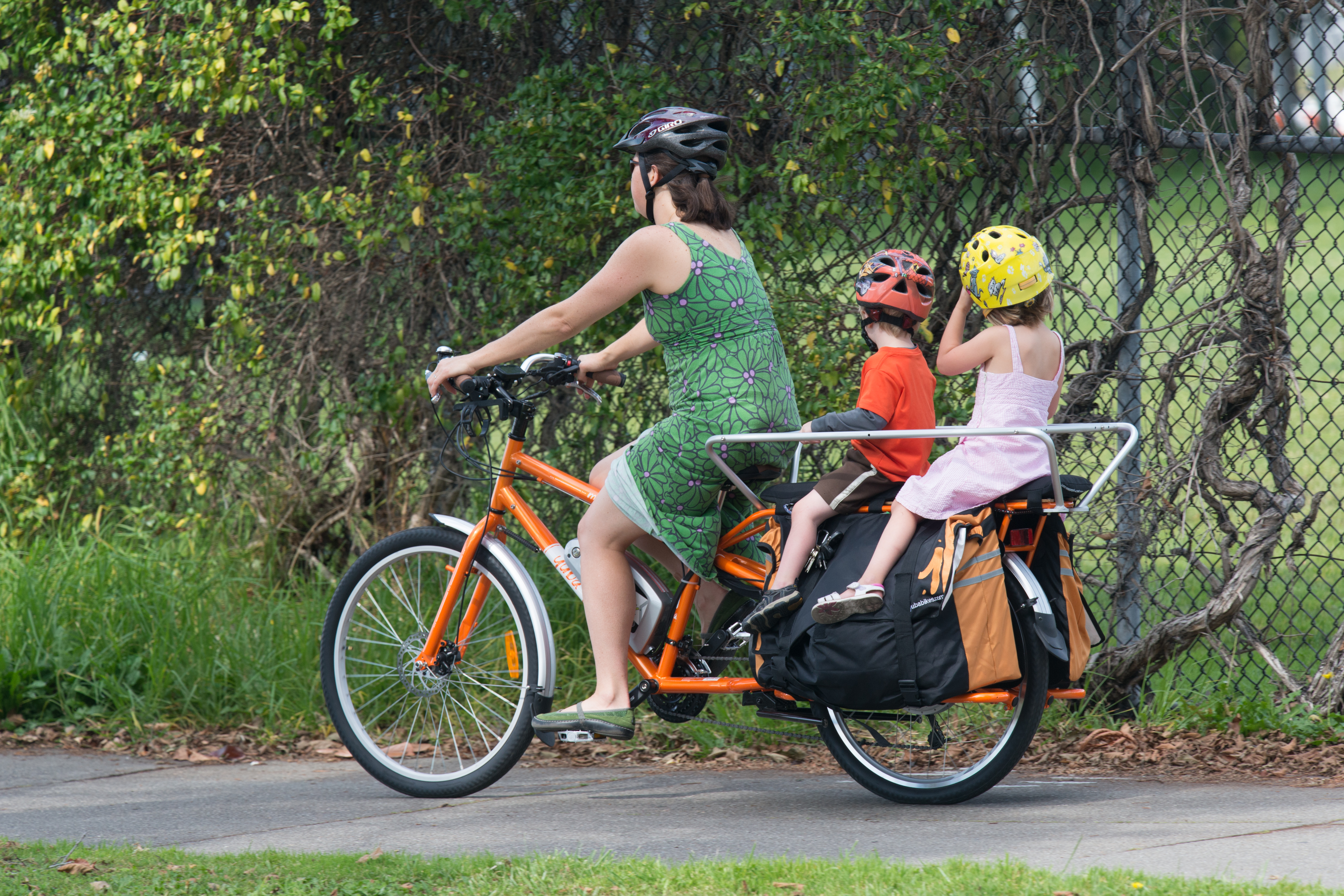 Woman with young boy and girl on bright orange tandem bicycle photo