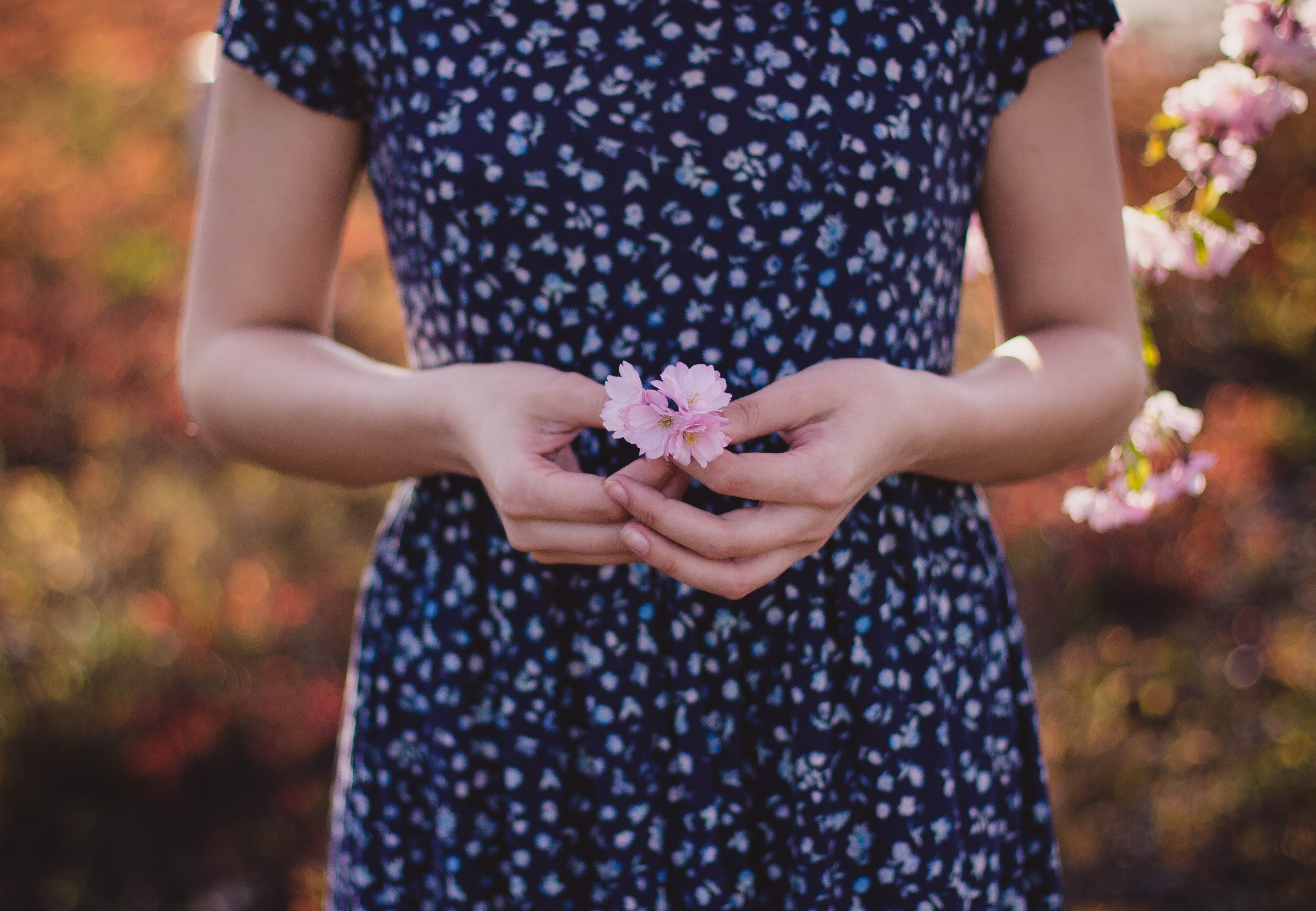Women in blue and white floral dress with pink flower on hand photo