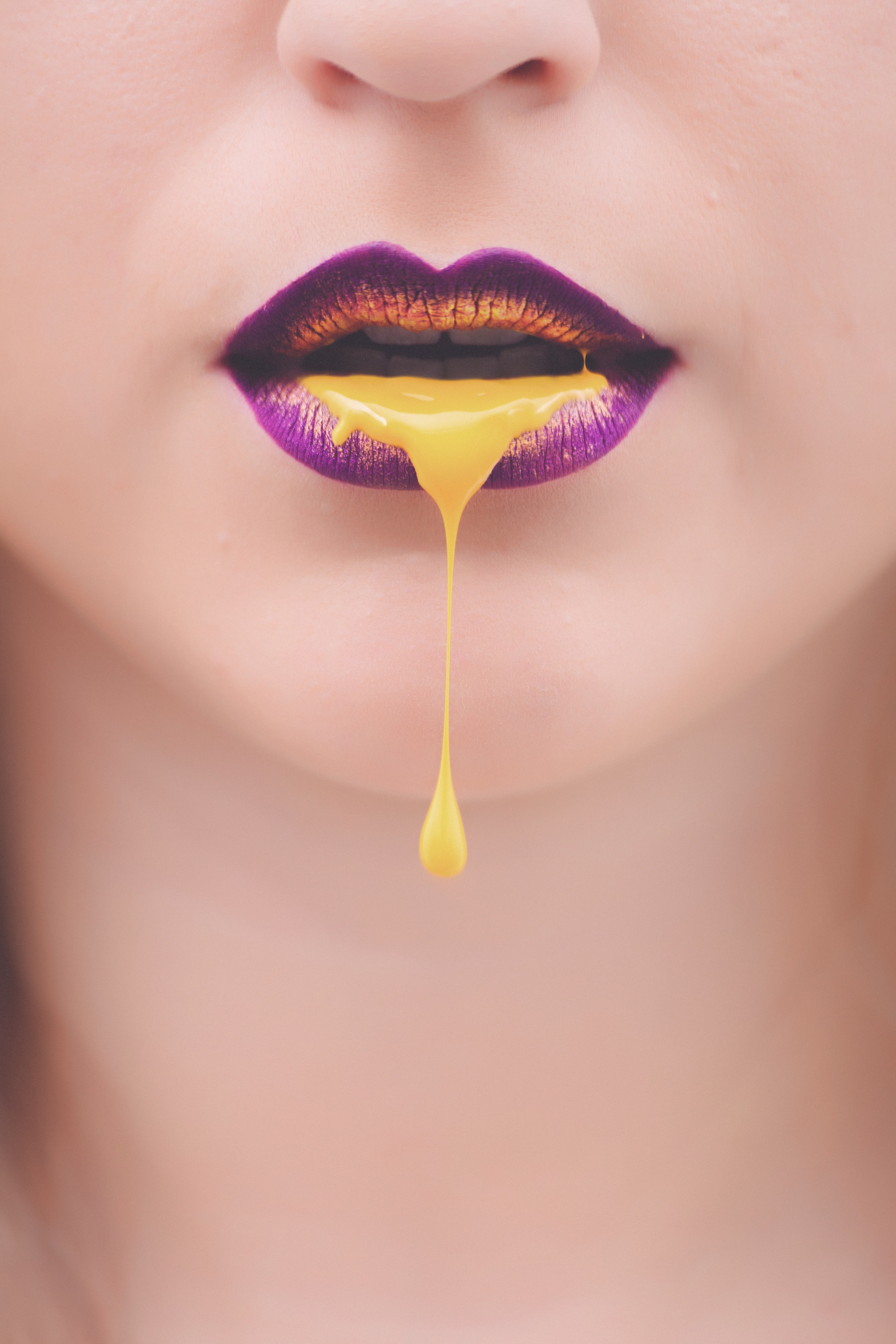 Women's purple and yellow lips with yellow liquid photo
