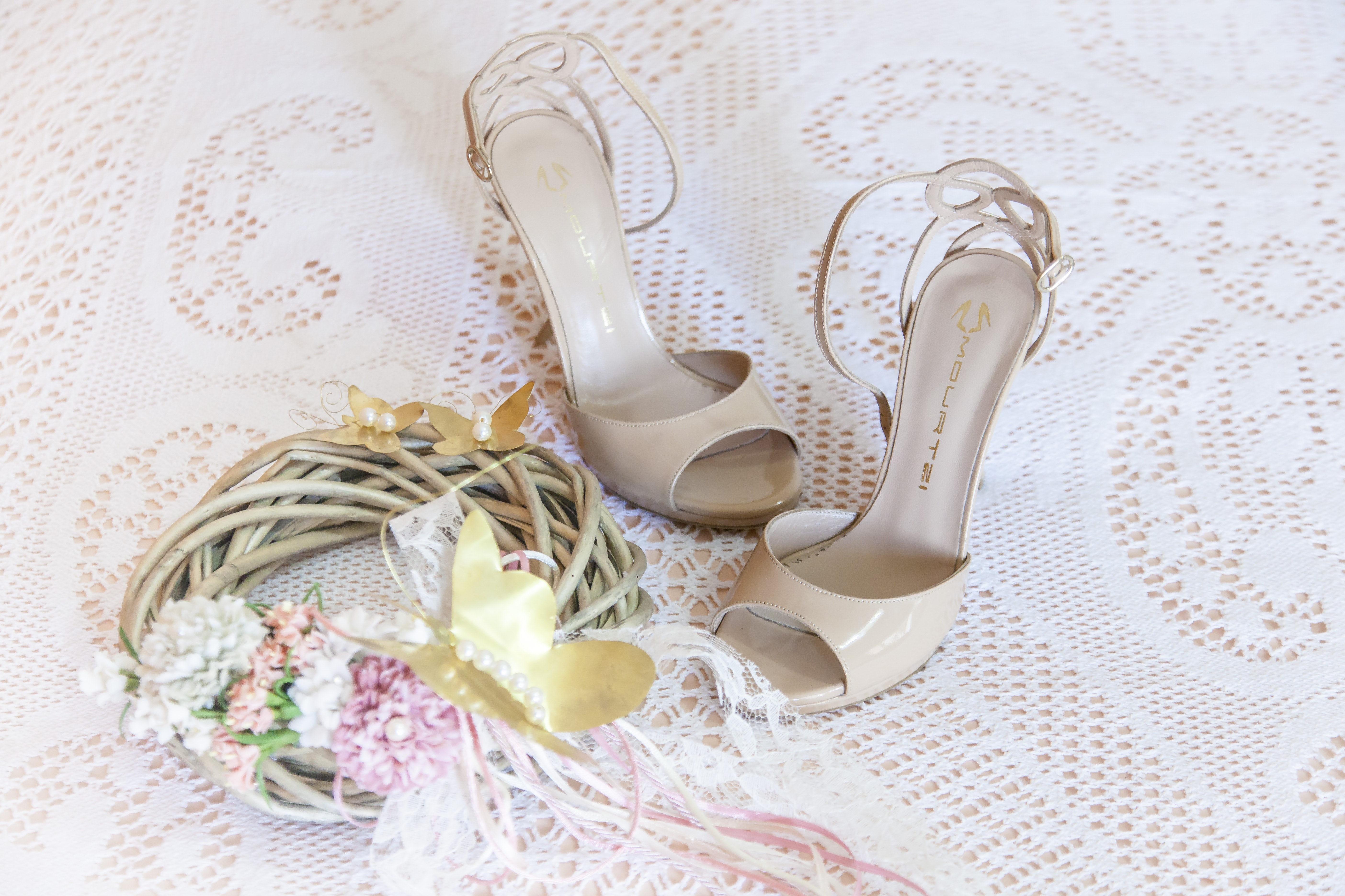 Women's white stiletto sandals on white floral design textile photo