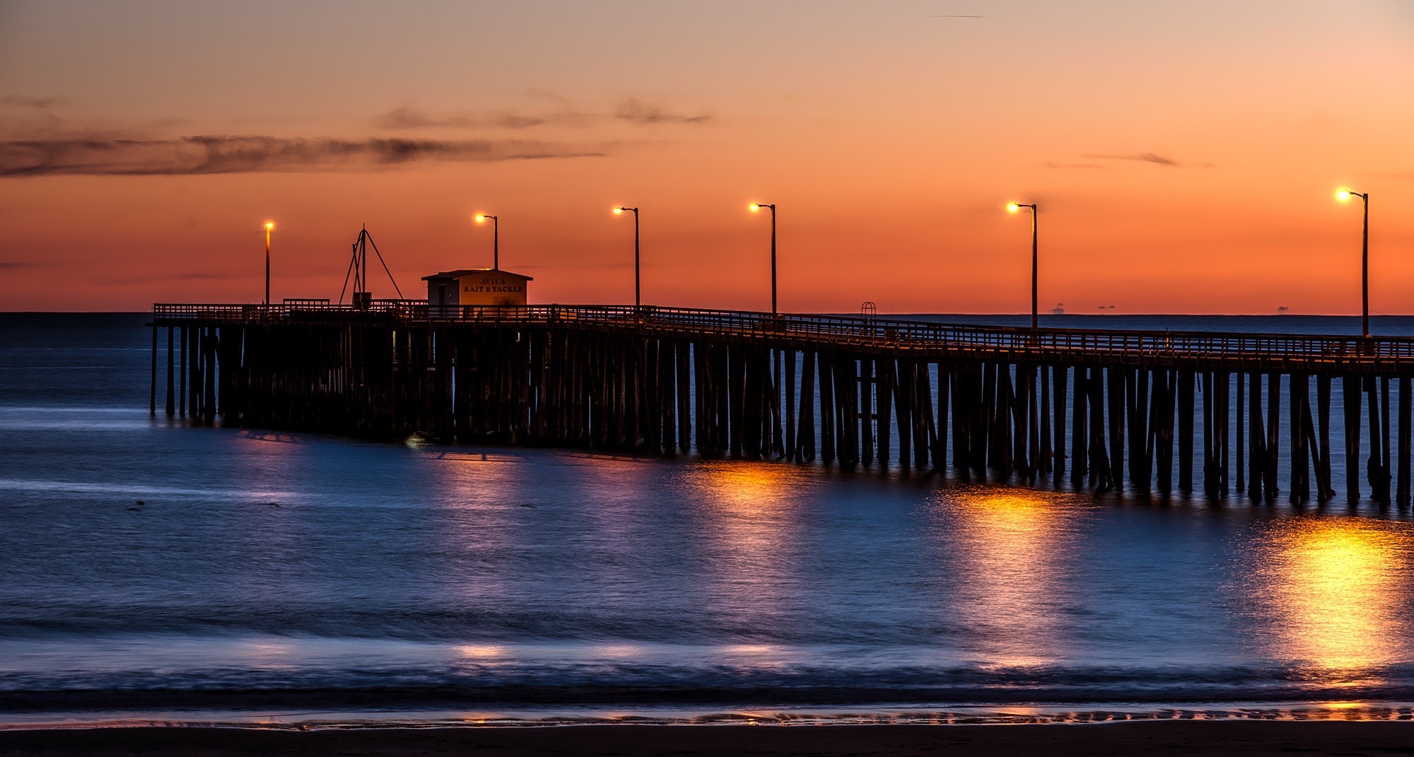 Wooden dock on sea shore with light post during sunset photo