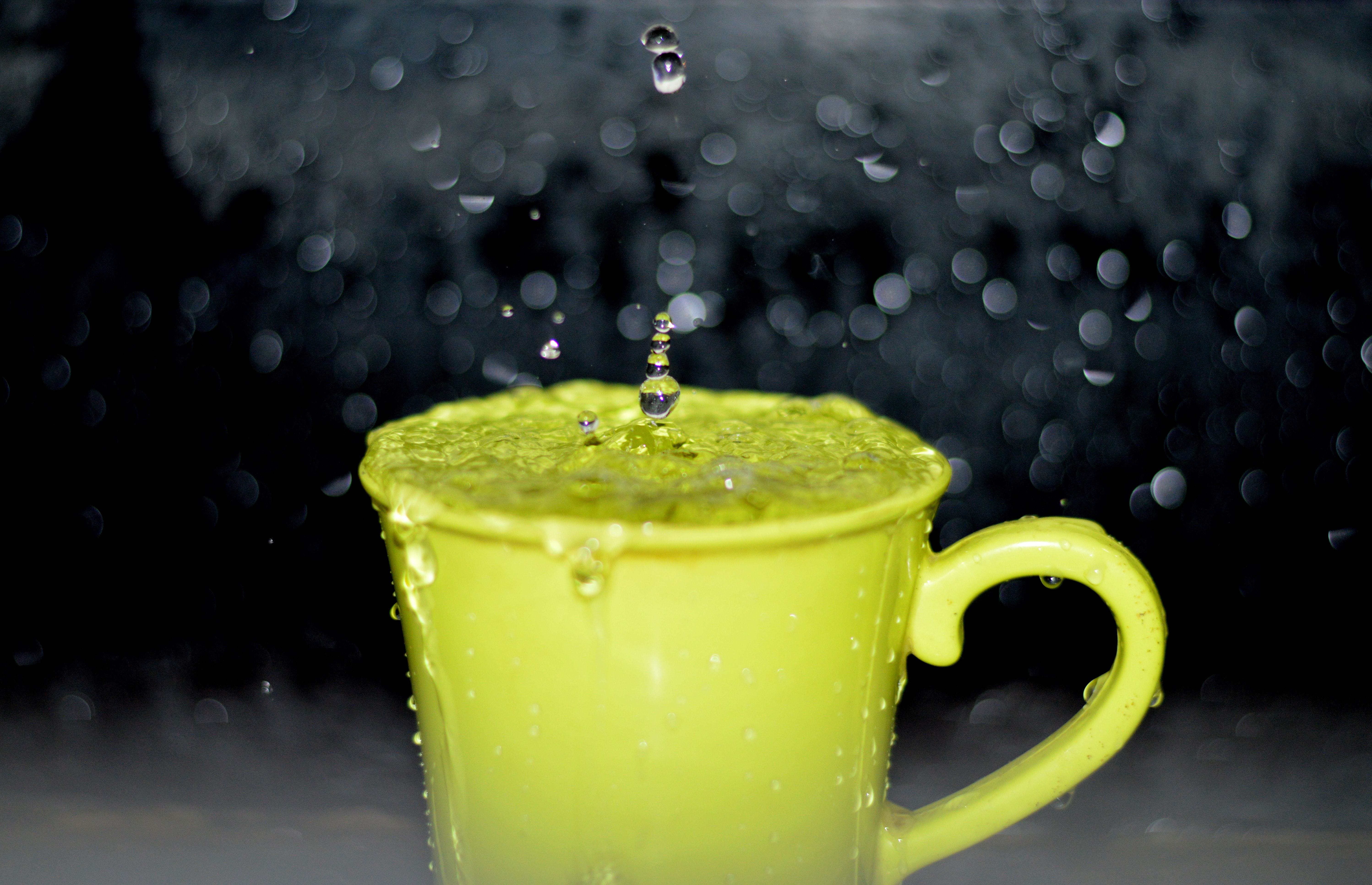 Yellow ceramic mug with water droplets in time lapse photography