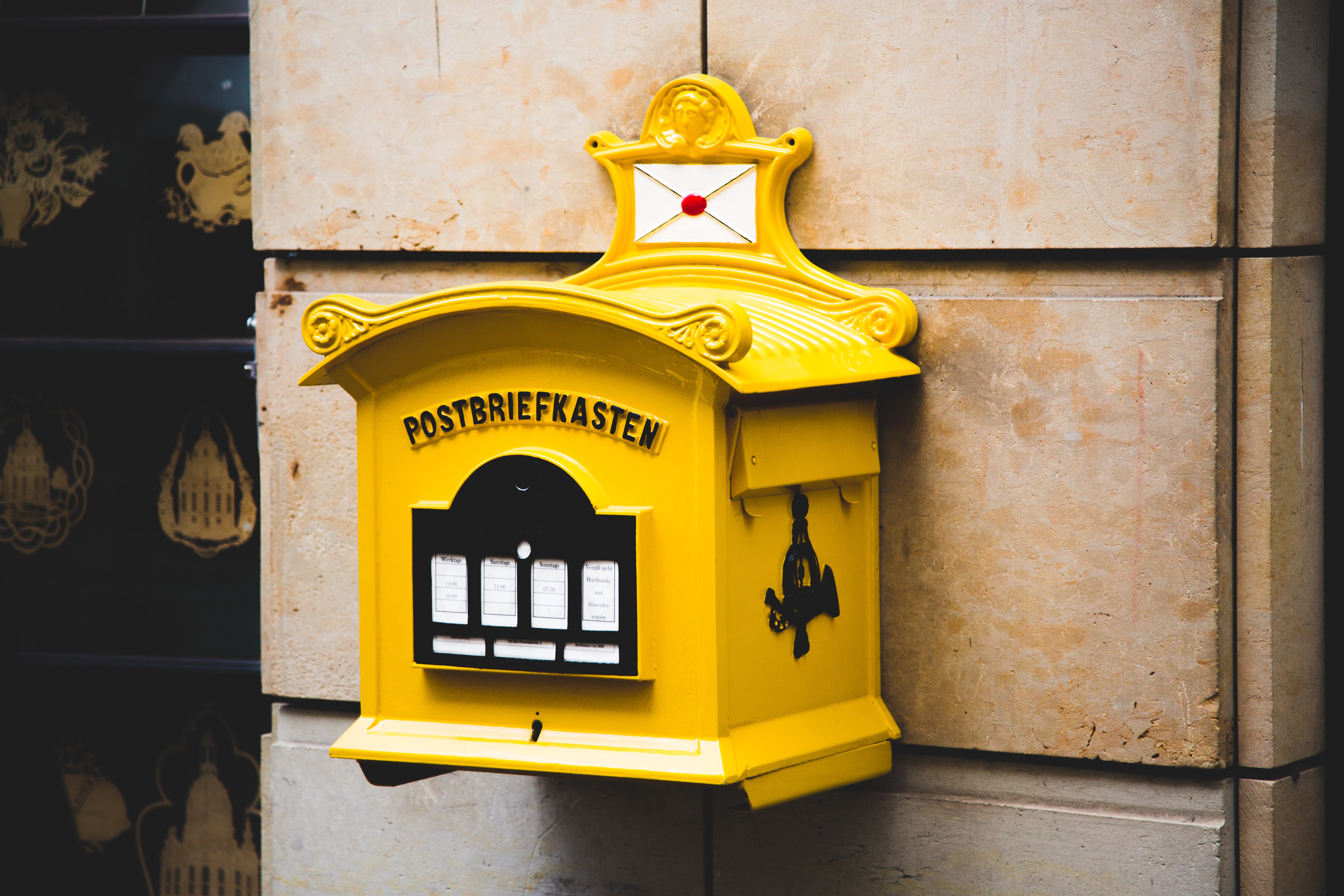 Yellow postbriefkasten floating mailbox on brown concrete wall photo