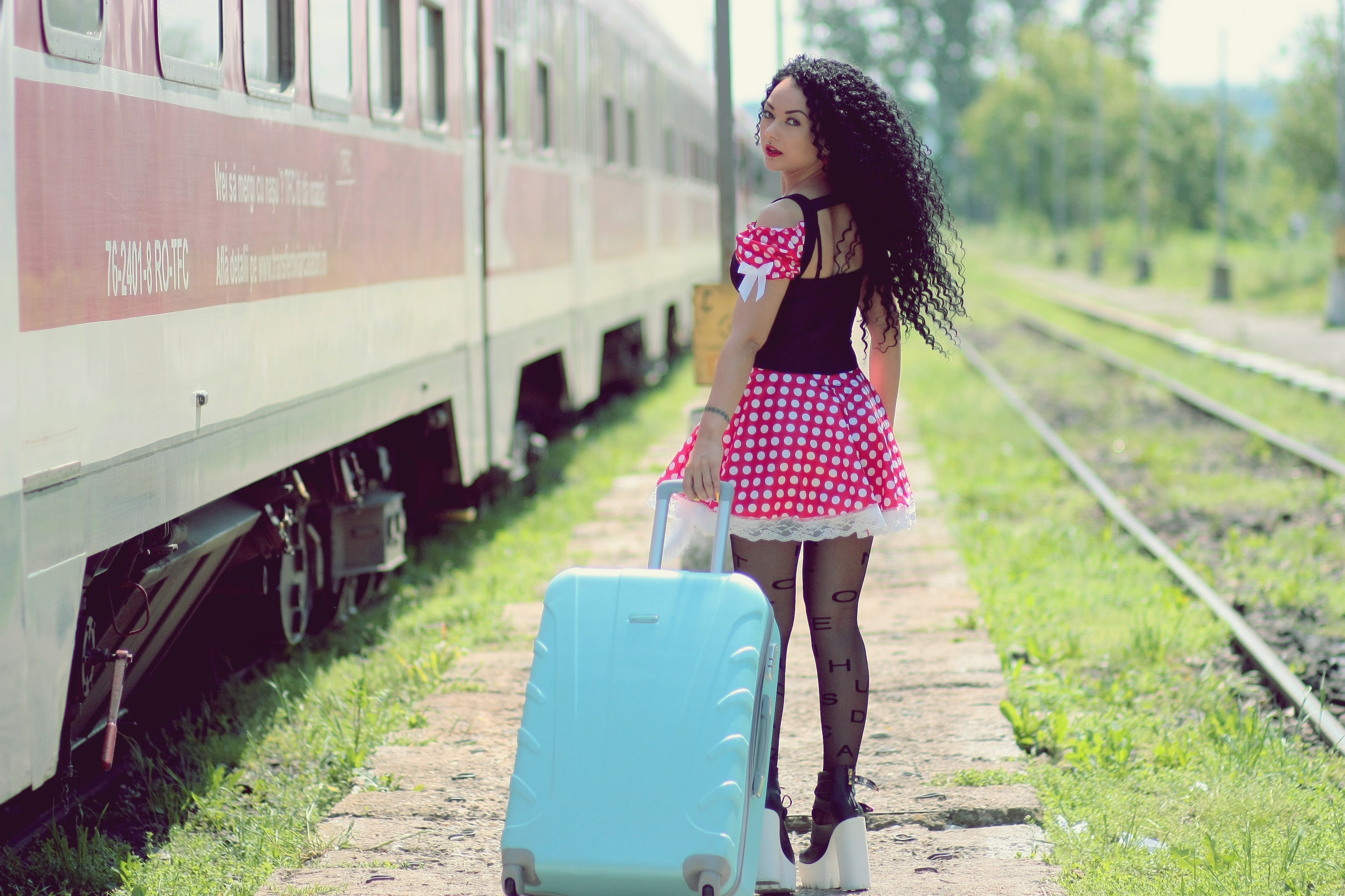 Young woman with luggage standing on train in city photo