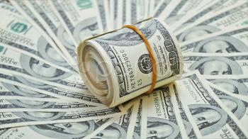 Rotating rolled bundle of 100 dollar notes on a money background ...