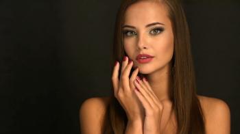 Closeup face of a beautiful young woman shows the red nails. Fashion ...