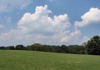 A large grass field with a blue sky