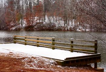 A snow covered dock by a lake