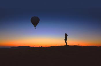 Alone person observes an hot air balloon at sunrise