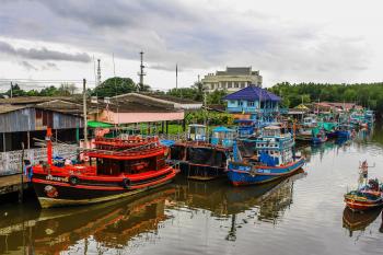 Assorted Color Boats on Body of Water Beside Houses and Trees Under White Sky at Daytime