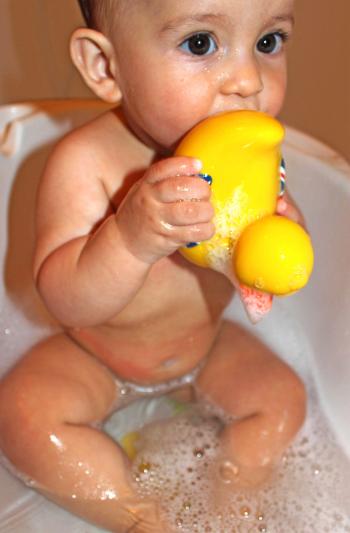 Baby bathing while holding and sucking a