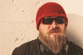Bearded Man Wearing Red Beanie Cap, Sunglasses ,and Black Jacket