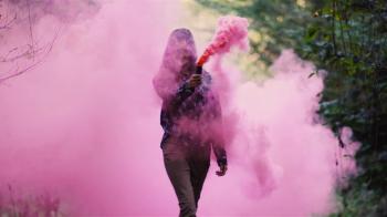 Beautiful girl in a forest spins around while holding a pink smoke ...