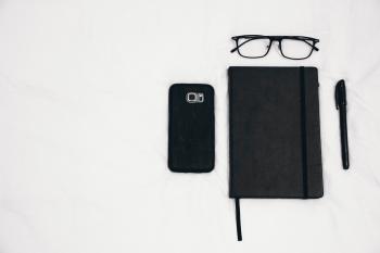 Black Smartphone Beside Planner and Eyeglasses and Pen