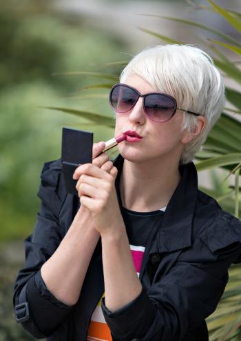Blond Short Haired Woman Applying Pink Lipstick Outside