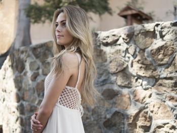 Blonde Haired Woman in White Dress Near Rock Wall in Daytime