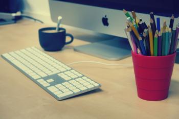 Blue Green and Black Colored Pencils on Red Plastic Cup Beside Silver Imac