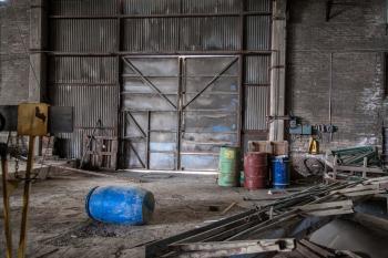 Blue Plastic Barrel on Floor Surrounded by Metal Pipe Inside Warehouse