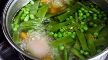 vegetables cooking in the boiling water in a saucepant on the stove ...