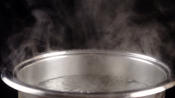 Boiling water in metal pan on black background, slow motion Stock ...
