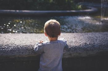 Boy in Gray Top Standing in Front of Water Fountain