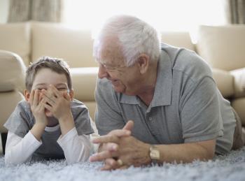 Boy and grandfather lying on floor and laughing - Sanitas a tu lado