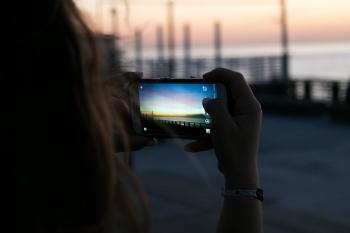 Brown Haired Woman Taking a Photo of Sunset