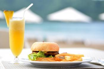 Burger With Lettuce and Fries on Plate Beside Pineapple Juice