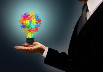 Businessman holding a jigsaw lightbulb - Ideas and creativity concept