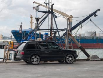 Car parked in front of fishing vessel and container ship at Viaduct Harbour