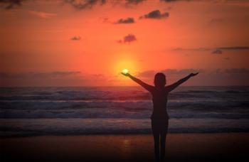 Celebrating life - A woman raises her arms at sunset