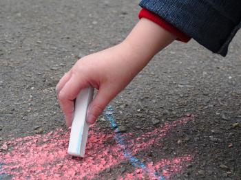 Child drawing with sidewalk chalk