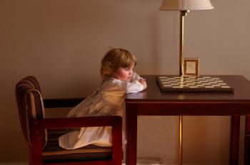 Child Setting on Chair in Front of Table