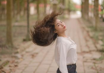 Closeup Photo of Woman in White Crew-neck Long-sleeved Shirt Shaking Her Hair in the Middle on Road