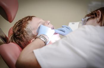 Dentist Woman Wearing White Gloves and White Scrubsuit Checking Boy's Teeth