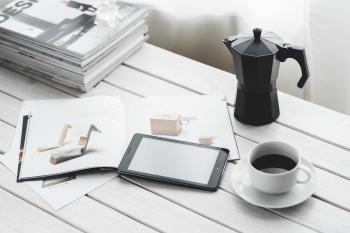 Digital tablet with cup of coffee on a white desk
