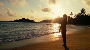 Lonely woman standing on empty beach at sunset, watching stormy ...