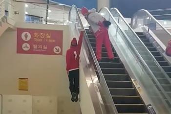 Olympian skier dangles one-handed up an escalator